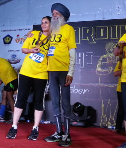 Fauja Singh presenting a medal to one of the winners at the Chardi Kala Night Run 2014 in Kuala Lumpur. The runner wore t-shorts bearing 103, his age at the time of the run.