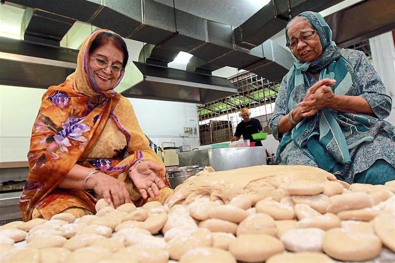 Niranjan Kaur (right) making capati with fellow volunteer Bhajan Kaur. — PHOTO / LOW LAY PHON / The Star 